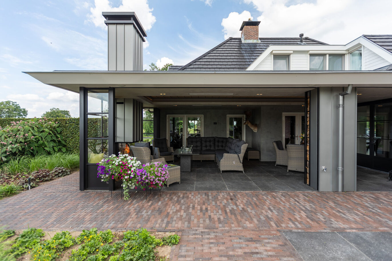 Maatwerk veranda met staal, glas en comfortabele loungehoek voor elk seizoen.